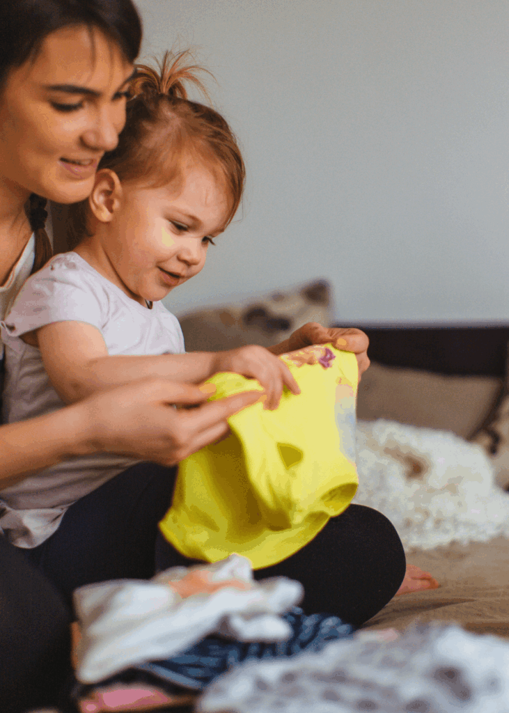 Gemeinsam den Haushalt schaffen Mutter und Kind legen gemeinsam Wäsche zusammen – Haushalt und Kinderbetreuung gleichzeitig meistern
