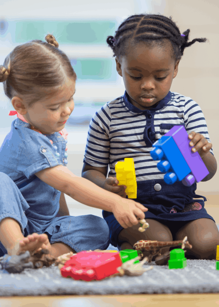 Eigenständiges Spiel in den Ferien zwei Kinder spielen allein und vertieft im Wohnzimmer – eigenständiges Spiel statt Dauerbeschäftigung