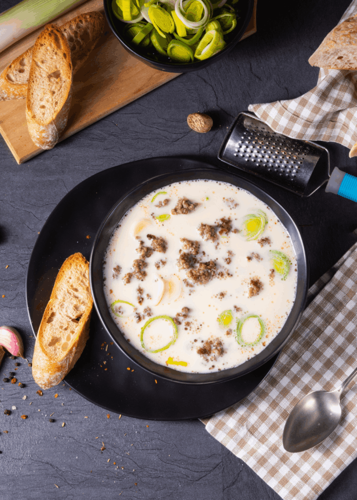 Käse-Lauch-Suppe mit Hackfleisch Cremige Käse-Lauch-Suppe mit Hackfleisch und Baguette in schwarzer Schale – Suppenrezept mit Lauch und Käse