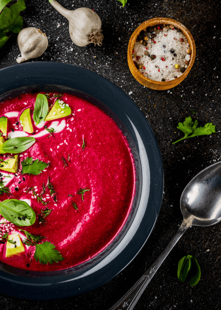Omas Rote-Bete-Suppe Pinke Rote-Bete-Suppe mit Avocado und Basilikum in dunkler Schale – Rote-Bete-Suppe Rezept nach Omas Art